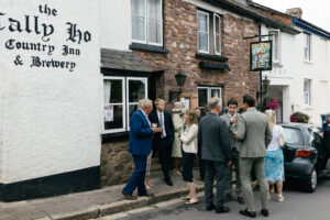 guests outside of the pub waiting for the wedding to start Rustic farm family wedding in devon