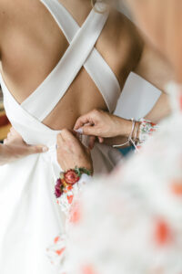 Photography of mother of the bride fastens dress for wedding