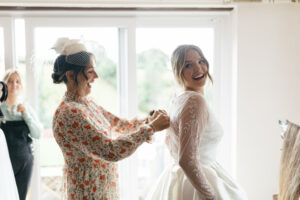 Mother of the bride helps fasten dress, Devon UK