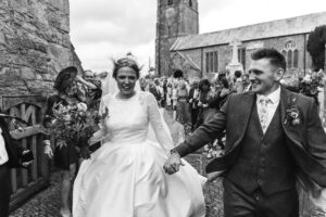 Bride and groom leave the church ceremony in black and white photography