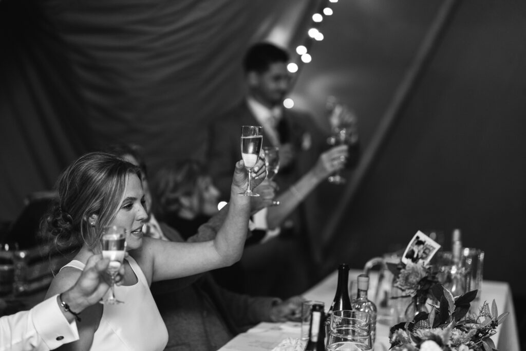 guests toast bride and groom during speeches black and white photos Rustic farm family wedding in devon
