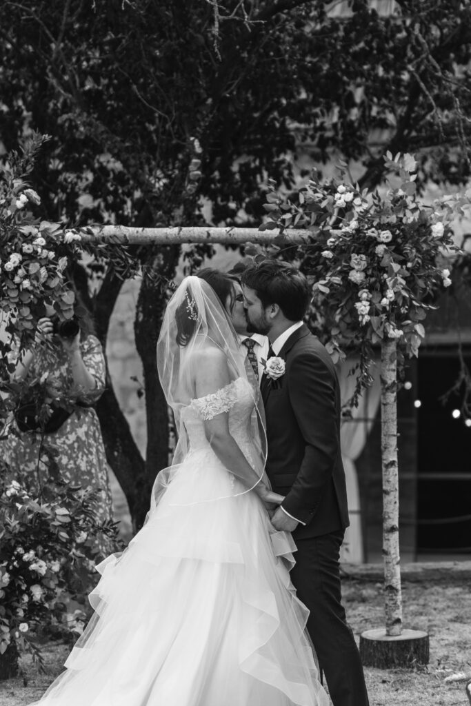 Bride and groom first kiss in the black and white candid photo