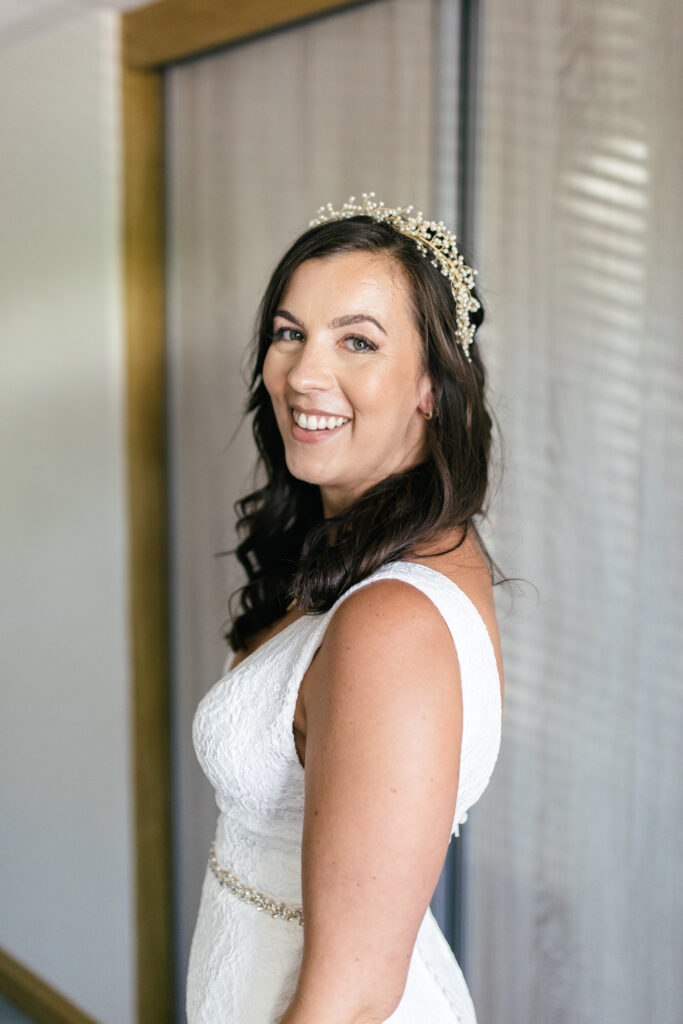 Bride looks at camera and smiles once she is ready for her wedding day 