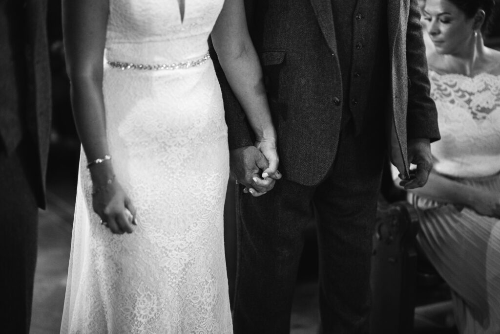 Bride and groom hold hands whilst getting married 