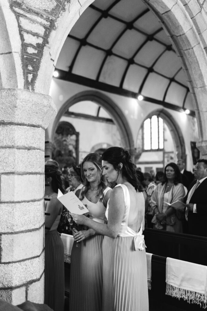 Bridesmaids hold order of service and sing a hymn 