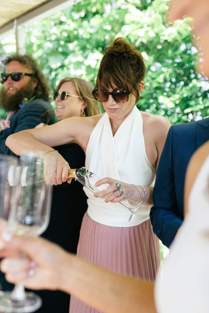 Bridesmaid pours champagne after the marraige ceremony 