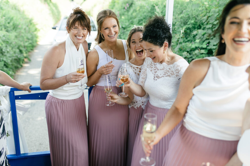 Bridesmaids enjoy a drink in the back of a tractor trailor on the way to the wedding reception