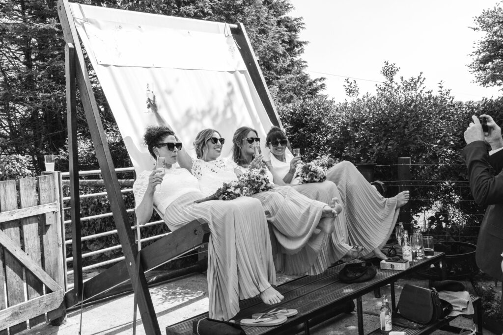 Bridesmaids relax in giant deckchair during the wedding reception on a family farm in Cornwall 