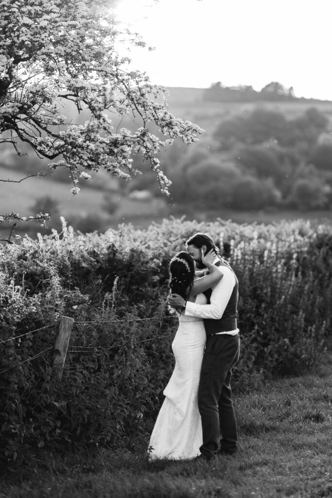 Couple kiss and hug during candid photograph at sunset 