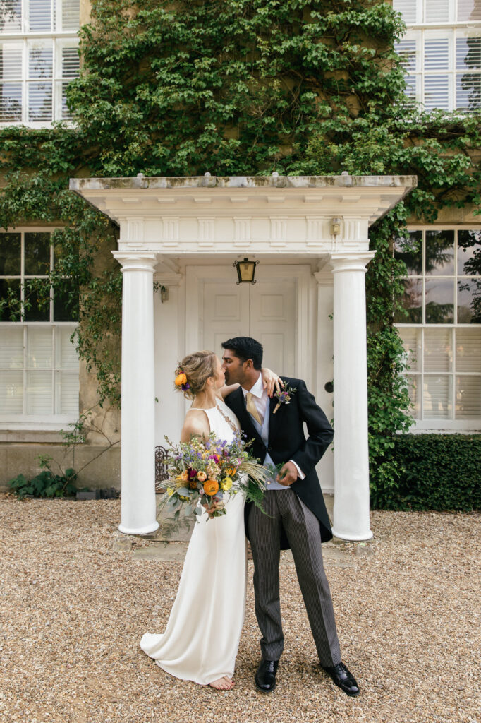 Bride and groom kiss outside of Northbrook park wedding venue 