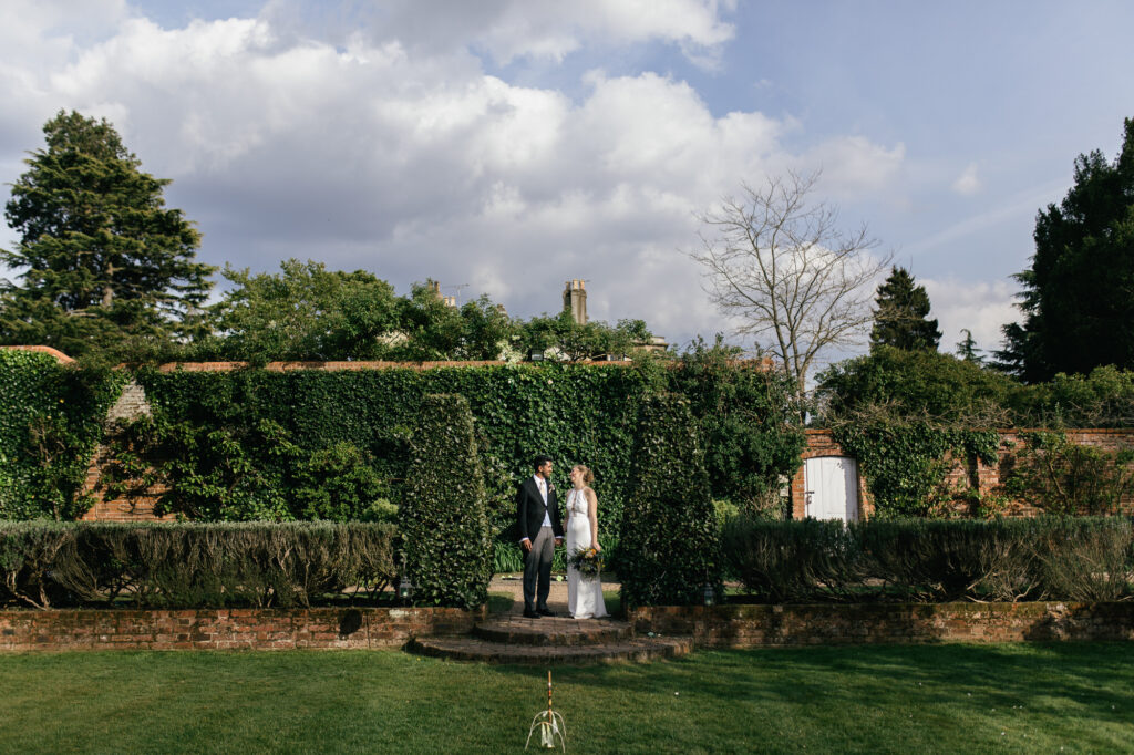 Bride and groom pose for photograph in the courtyard garden at Northbrook park 