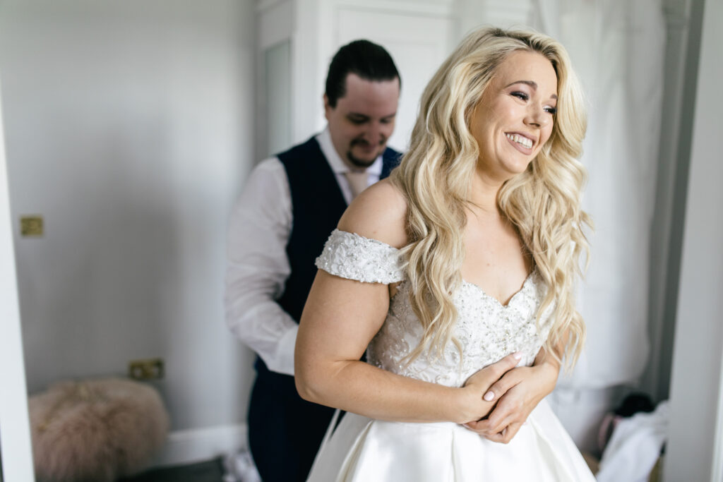 Bride has her wedding dress zipped up 