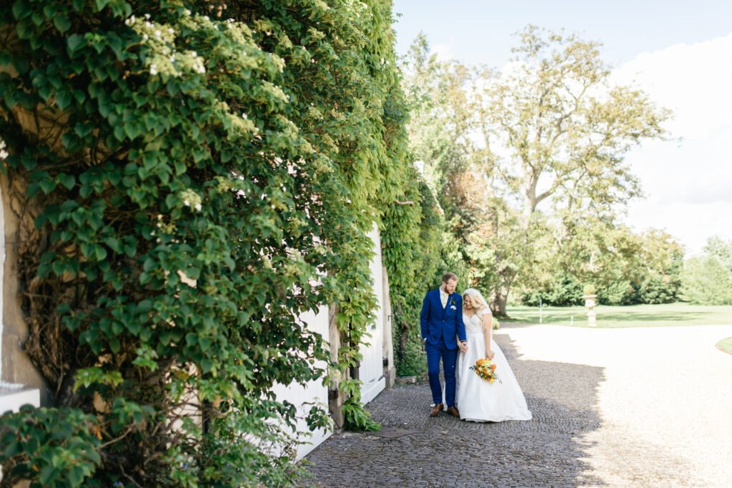 Bride and groom walk along the sunny gardens on thier wedding day