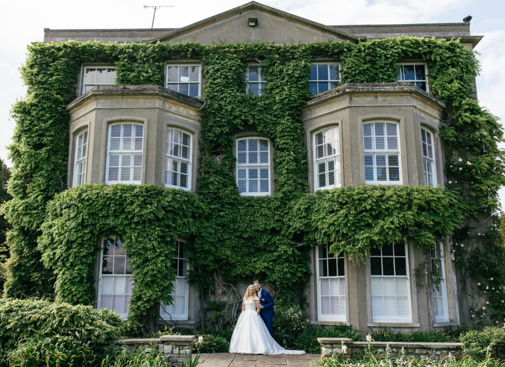 Bride and groom stand outside of Northbrook park wedding venue on a sunny summers wedding day 