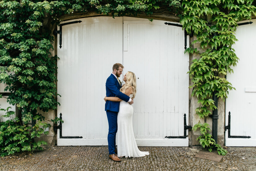 Bride and groom sgtand outside barn doors and pose for a wedding photo