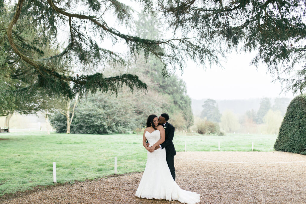 Groom stands behind bride and hugs her